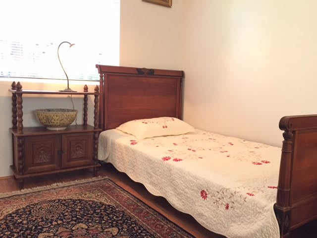 A cozy bedroom with a single bed, nightstand, and traditional decor.