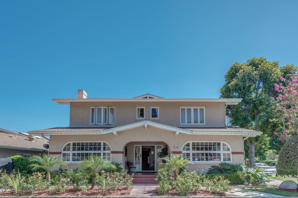 A classic two-story house with a well-maintained front yard under a clear blue sky.
