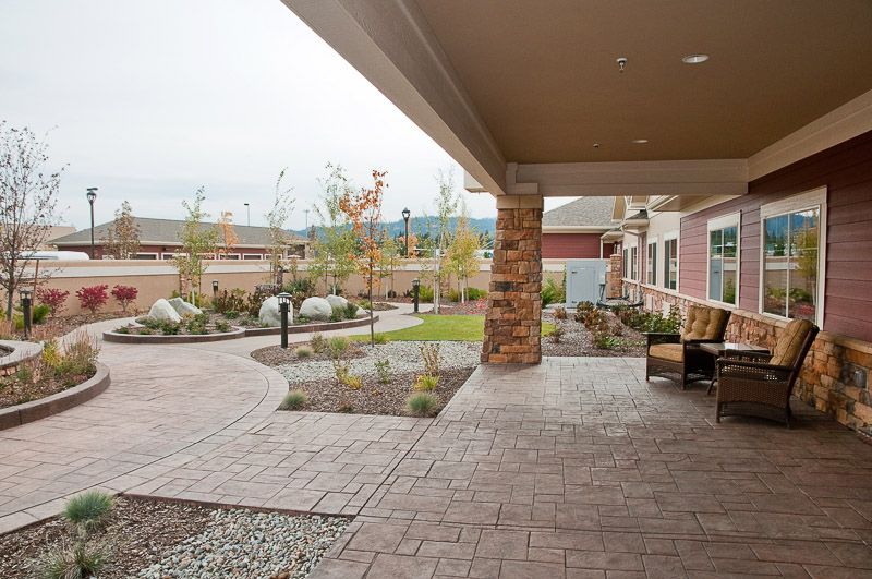 A covered patio with seating overlooks a landscaped garden and walkway.