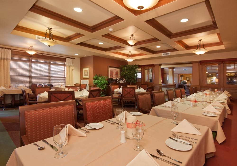 A well-lit restaurant dining area with neatly arranged tables and chairs, featuring elegant table settings.