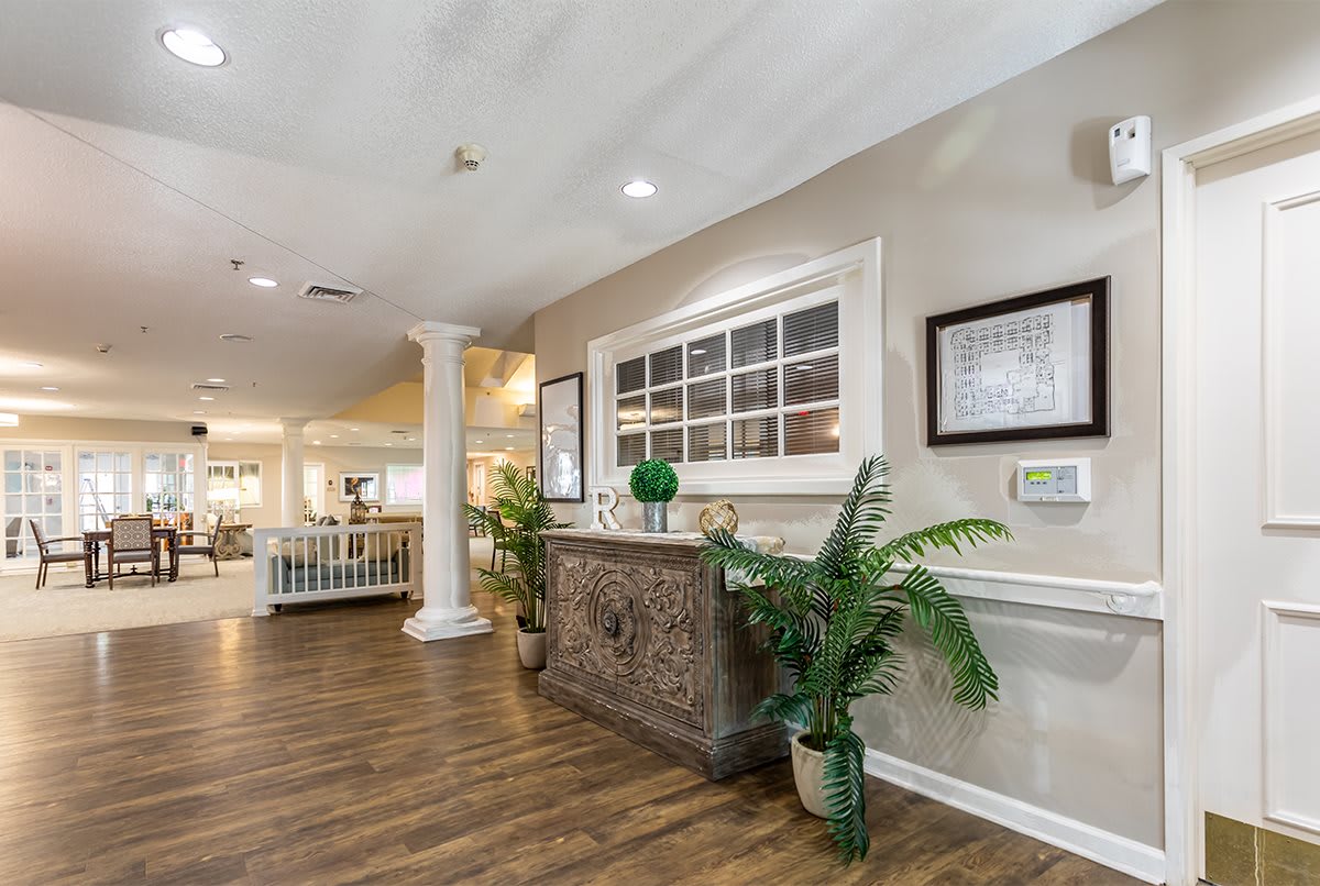 A stylish reception area with decorative furniture and lush plants, complemented by wooden flooring and modern decor.