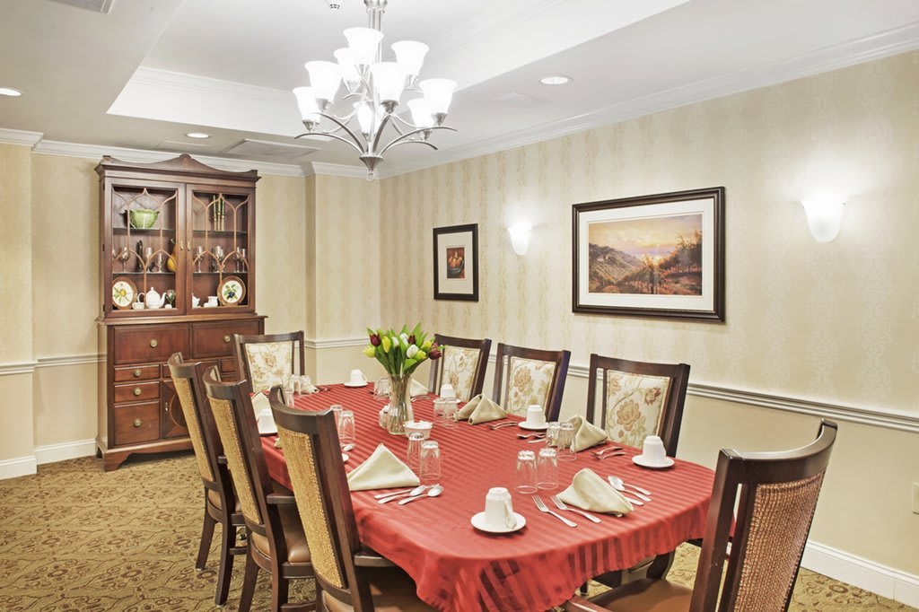 Elegant dining room with a red tablecloth, decorated settings, and classic furnishings.