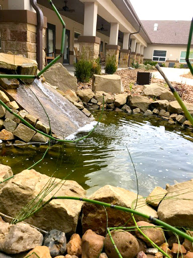 A tranquil pond with a cascading waterfall, surrounded by natural stones and greenery.
