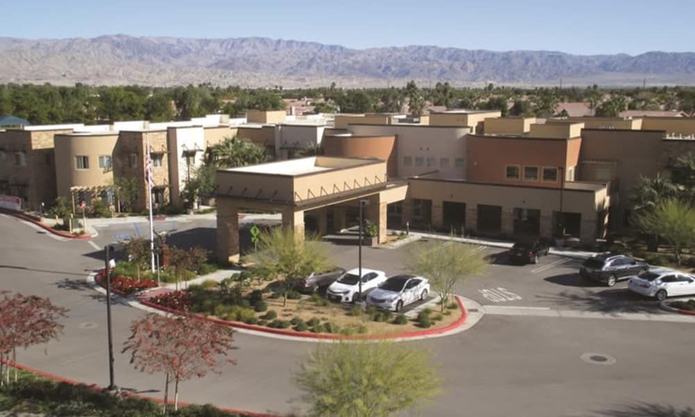 A hotel surrounded by desert landscaping and mountains in the background.