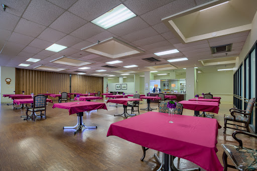 A spacious dining area featuring tables dressed with pink tablecloths, ready for guests.