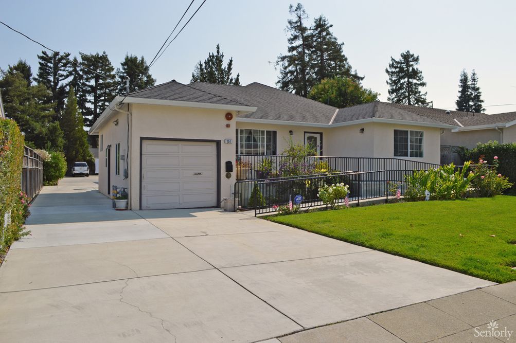 A suburban house with a driveway and garage, surrounded by a well-maintained lawn and trees.