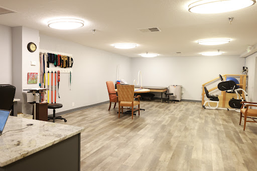 A spacious rehabilitation room featuring various furniture and exercise equipment.