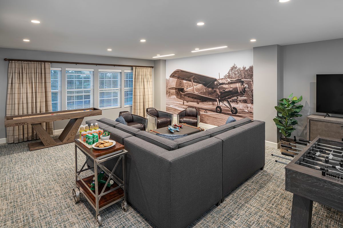 A modern living room with a sectional sofa, airplane-themed mural, and ample natural light.