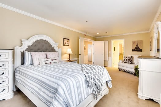 A cozy bedroom with a striped bedspread, comfortable seating, and warm lighting.