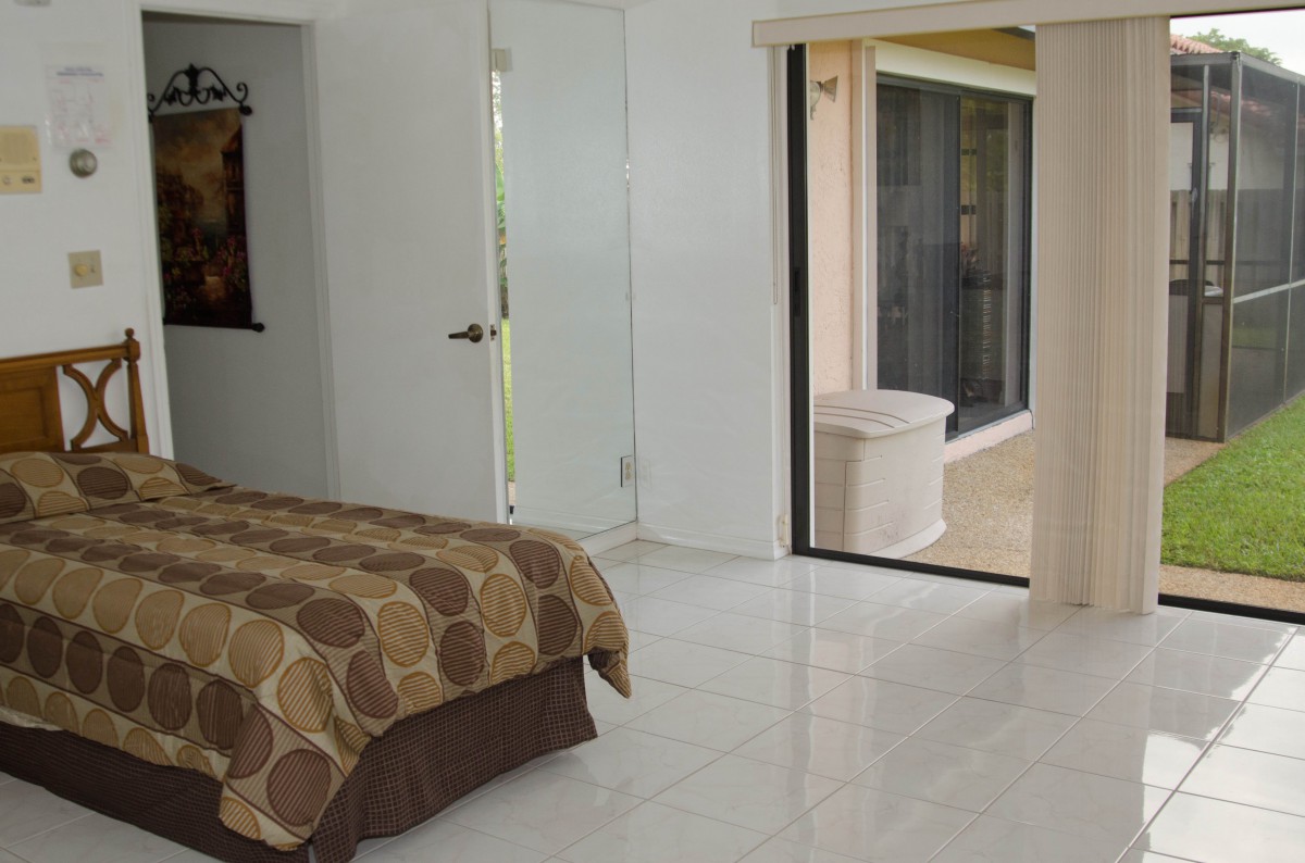 A minimalist bedroom with a bed and an open sliding door leading to a patio.