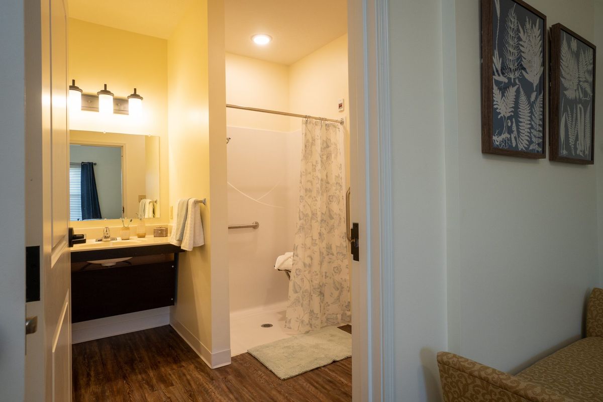 A well-lit bathroom featuring a walk-in shower and a vanity with a sink and mirror.