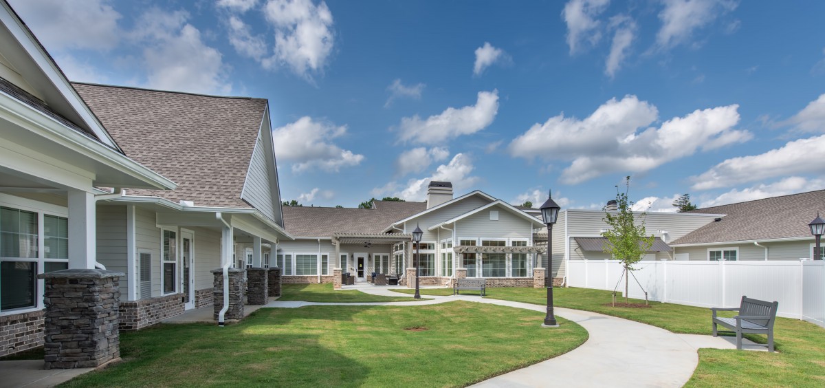 A modern residential building with a well-maintained lawn under a clear blue sky.