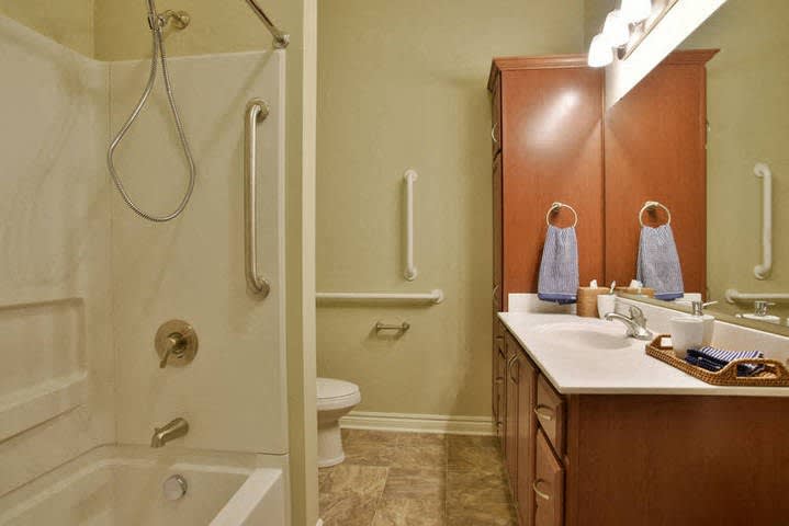 A well-organized bathroom featuring a shower, sink, and wooden cabinets.
