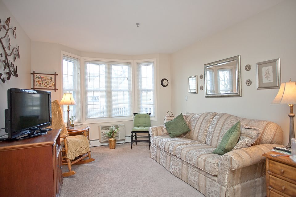 A cozy living room with a sofa, chairs, and a large window.