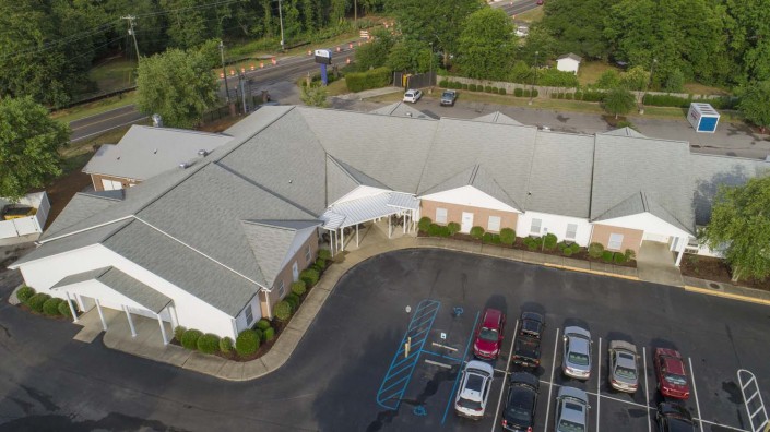 Aerial view of a building with a parking lot and surrounding greenery.
