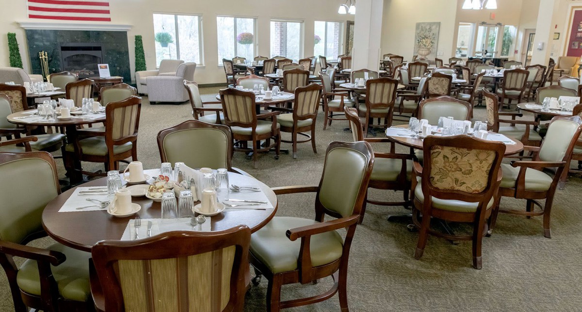 An empty dining room with neatly arranged tables and chairs, set for guests.