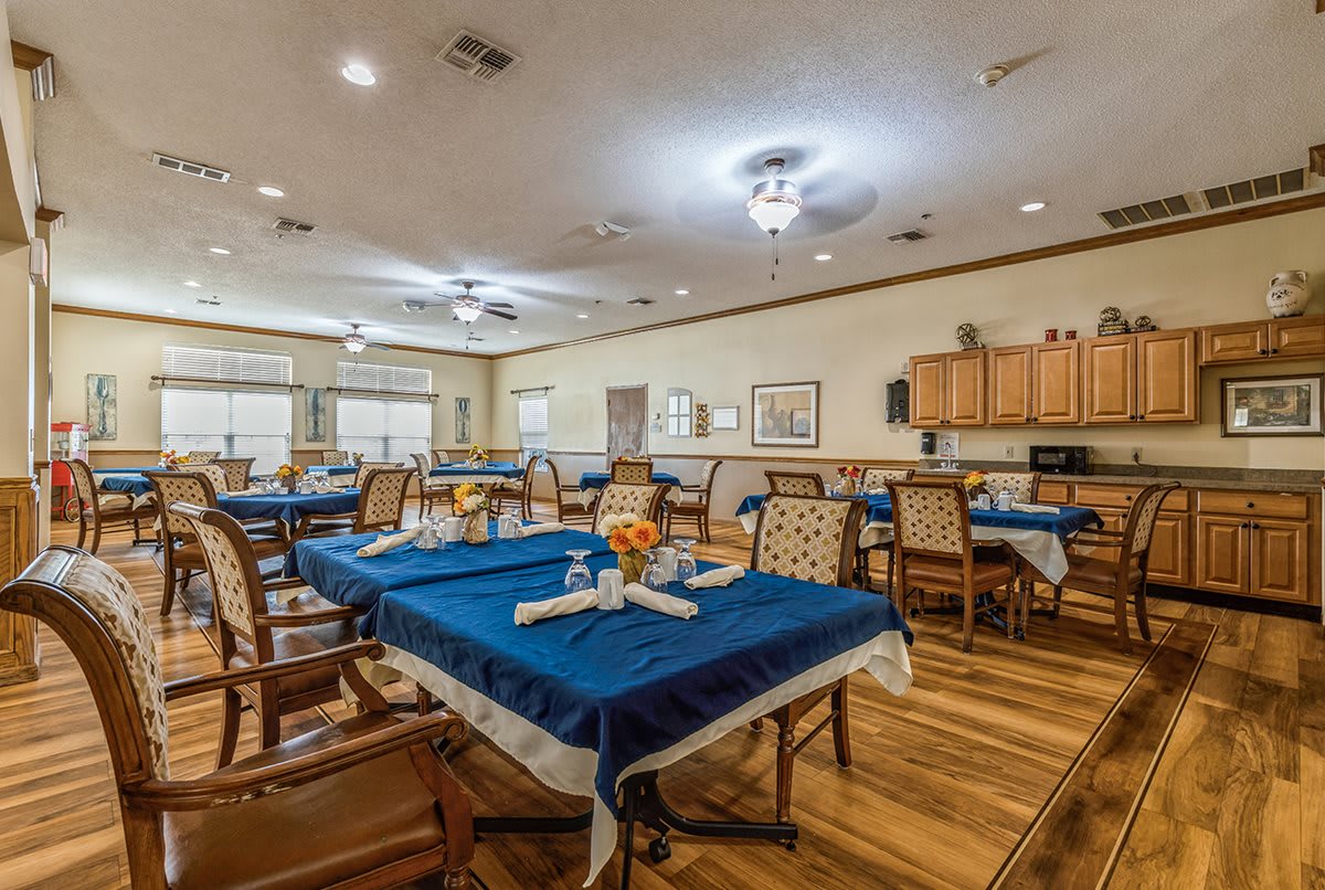 A spacious dining area with blue tablecloths and neatly arranged tables and chairs.