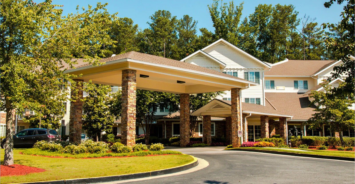A building entrance with a covered driveway and surrounding trees.