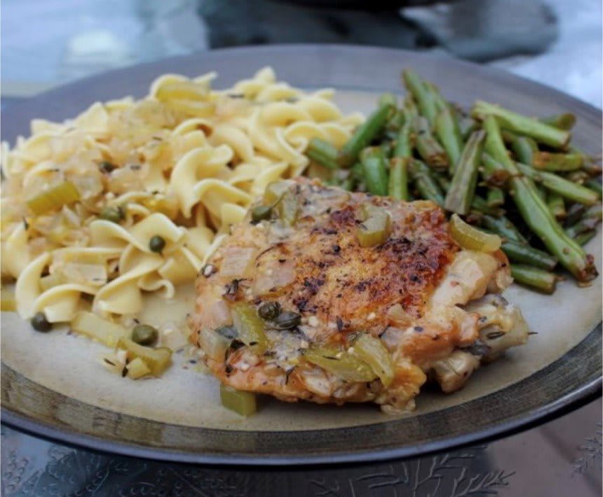 A plated meal featuring baked chicken, noodles, and green beans.