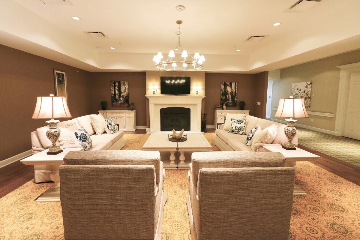 A spacious, elegantly designed living room featuring a central fireplace and luxurious seating.