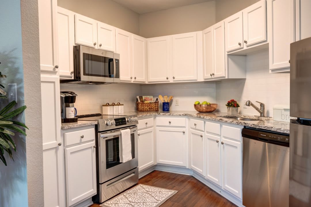 A modern kitchen with white cabinets and stainless steel appliances.