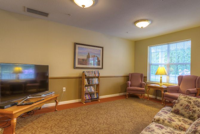 A cozy living room with a television, bookshelf, and comfortable seating.