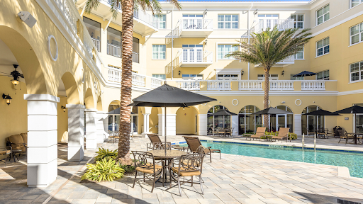 A serene outdoor pool area surrounded by palm trees and comfortable seating, perfect for relaxation.