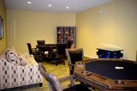A cozy indoor game room featuring poker tables, chairs, and a sofa.