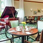 A cozy dining area featuring a grand piano and elegantly set tables.