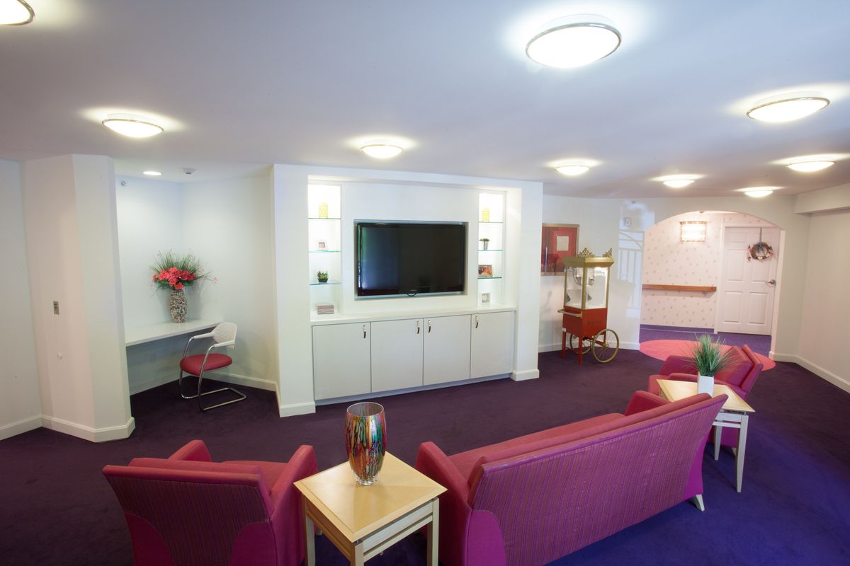 A modern lounge area featuring a large television and colorful seating.
