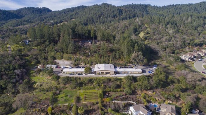 Aerial view of a building complex nestled in a forested mountainous area.