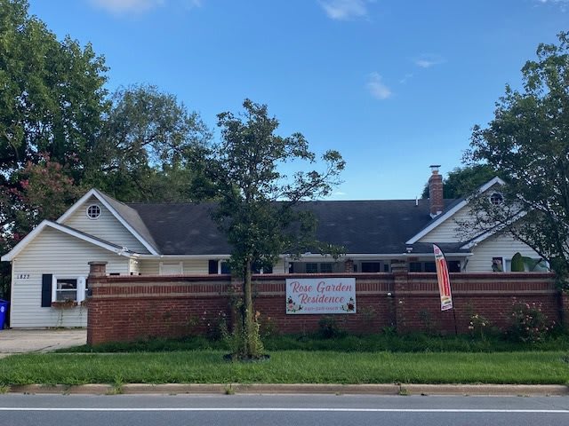A house with a wooden fence and banners along a roadside.