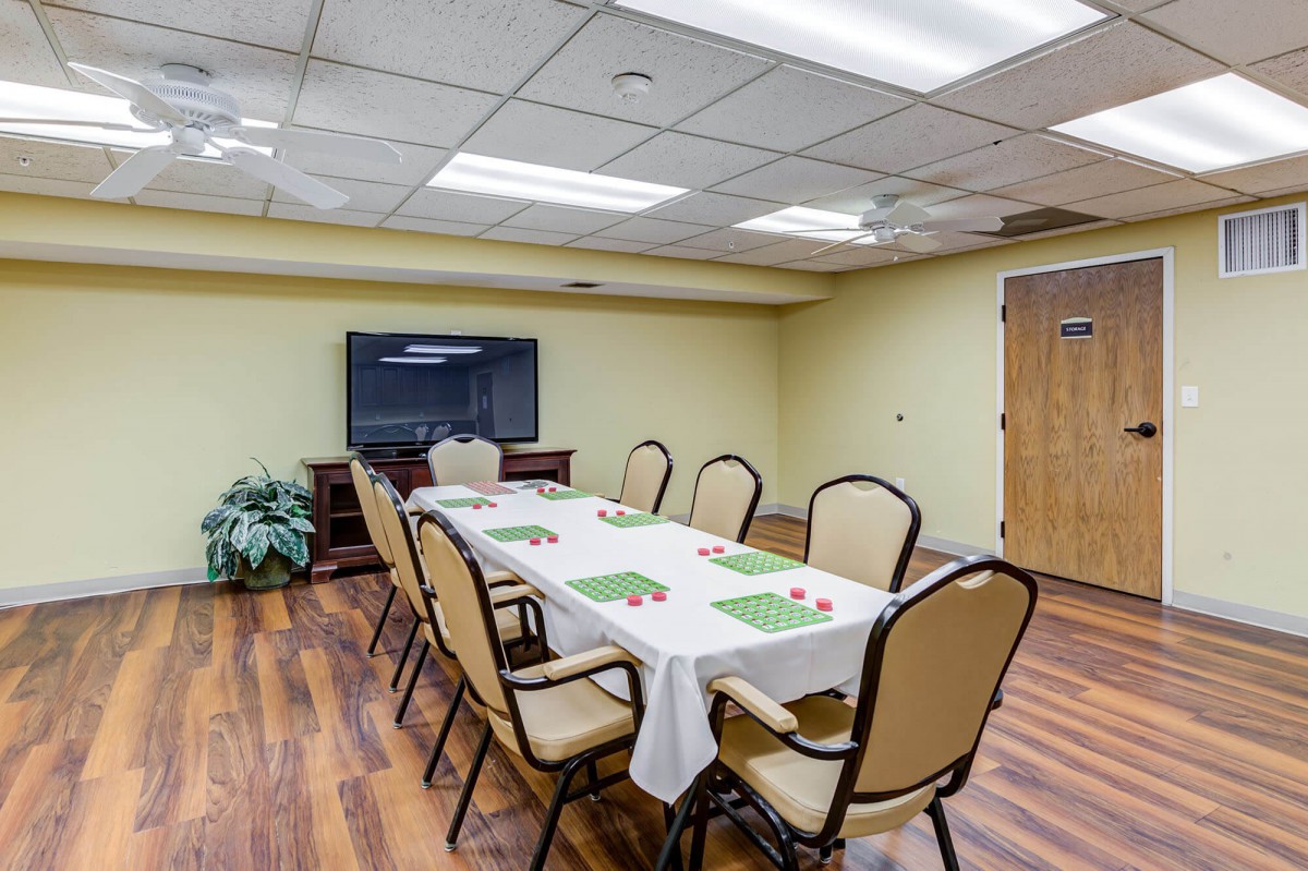 A small meeting room with a conference table, chairs, and a television.