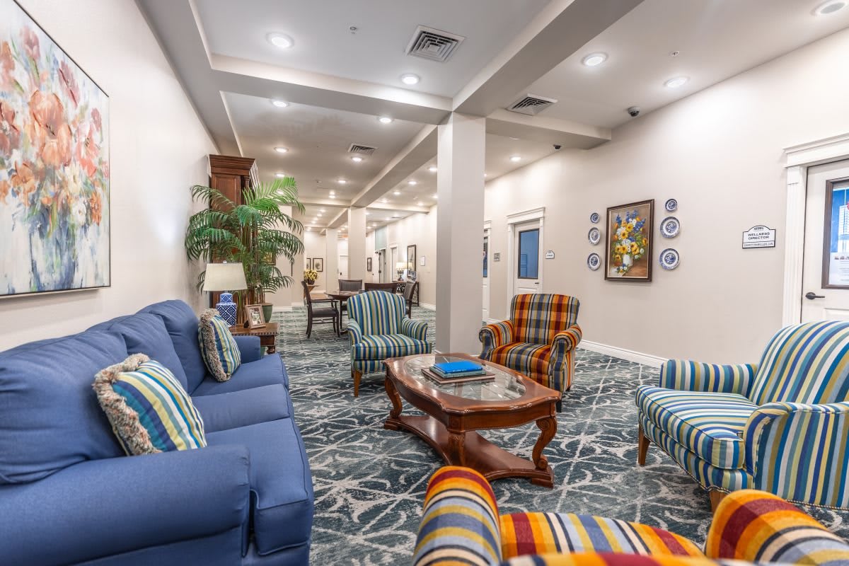 A spacious and elegantly decorated living room area featuring comfortable seating, a wooden coffee table, and vibrant artwork.