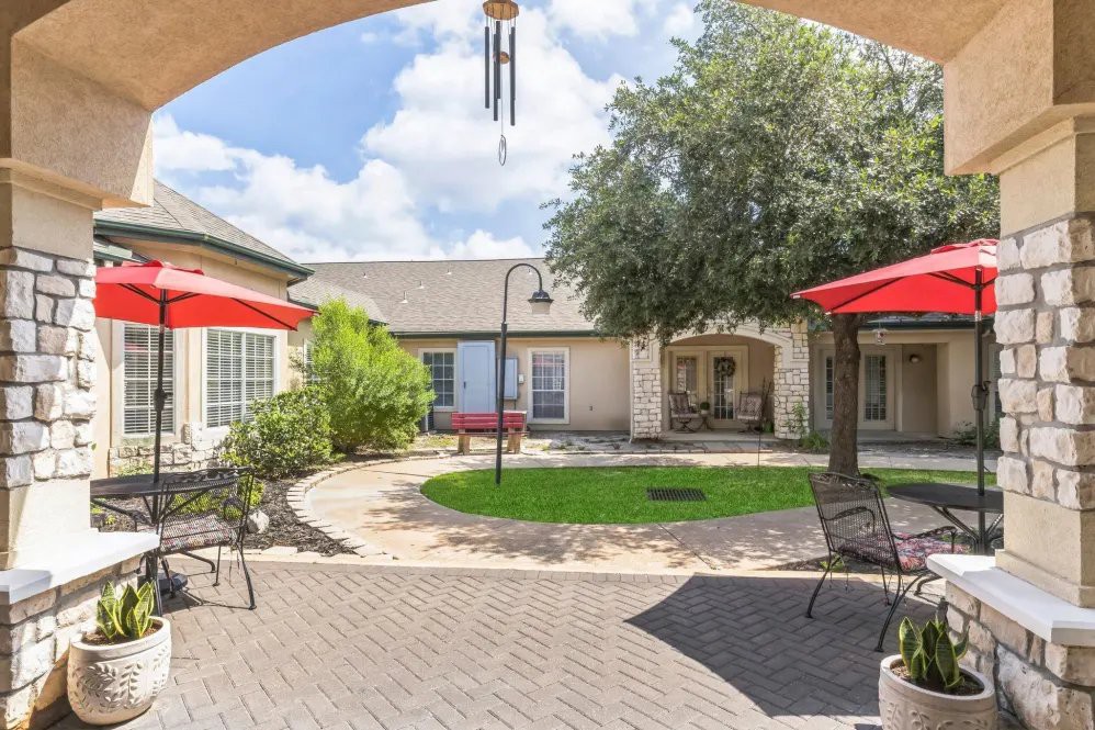 A sunny courtyard with outdoor seating and red umbrellas.