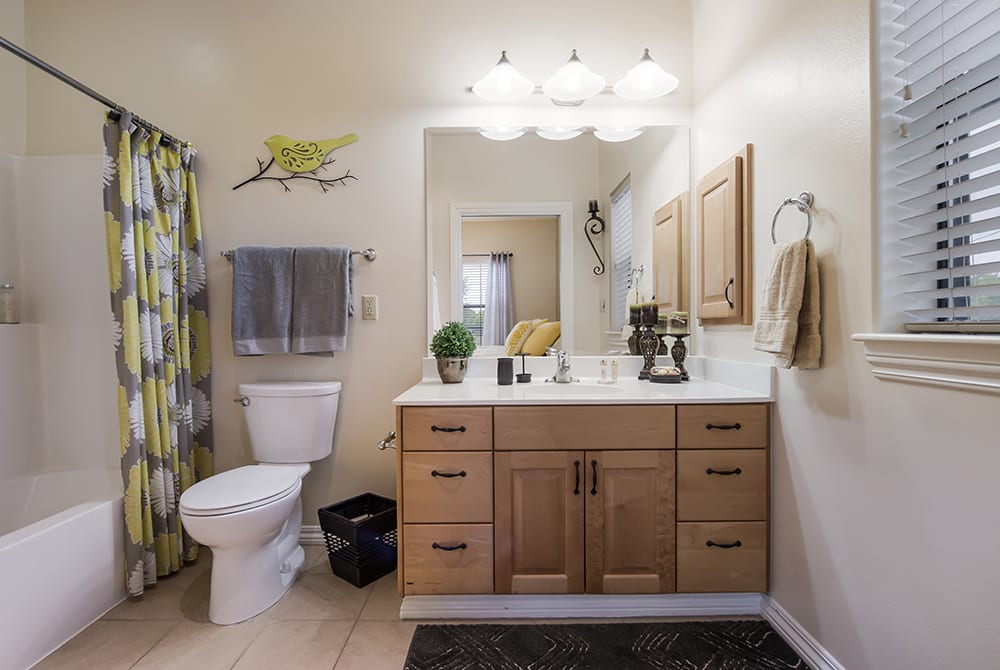 A modern bathroom with a wooden vanity, large mirror, and warm lighting.