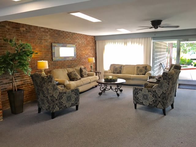 A cozy living room with sofas and armchairs arranged around a coffee table, accented by a brick wall.