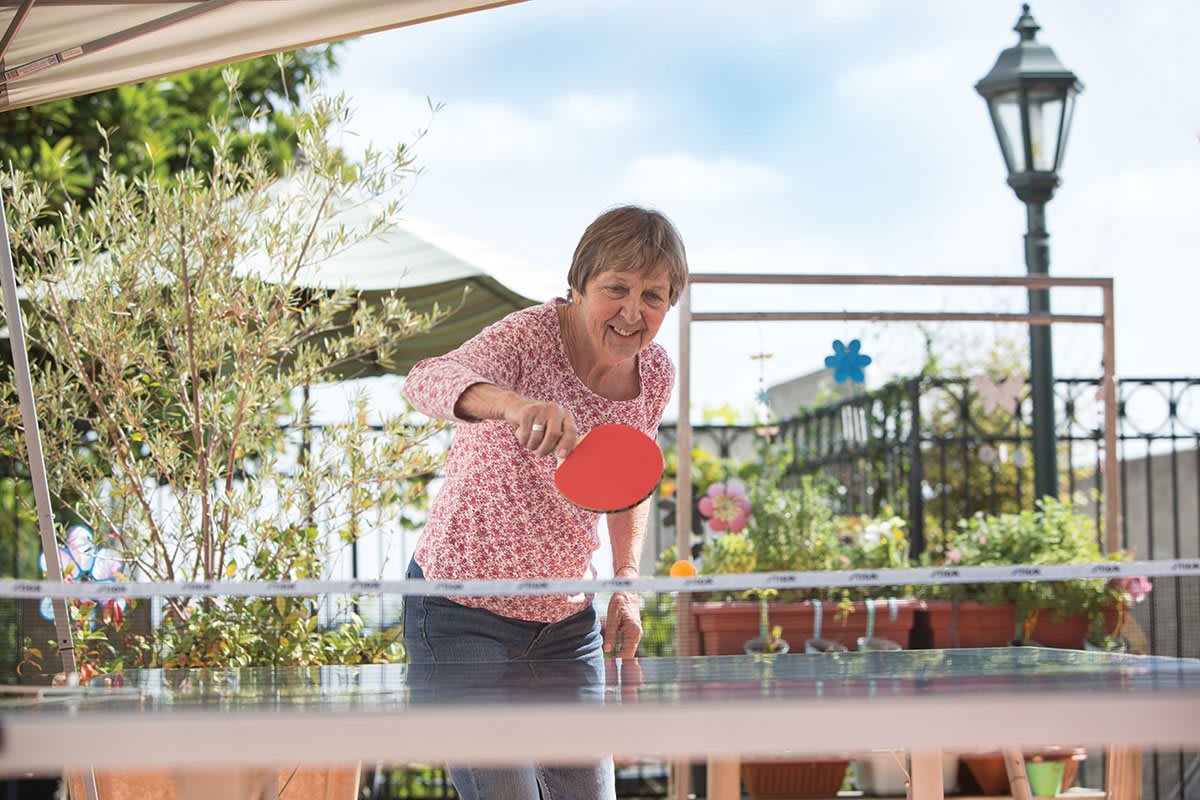 A woman playing table tennis outdoors.