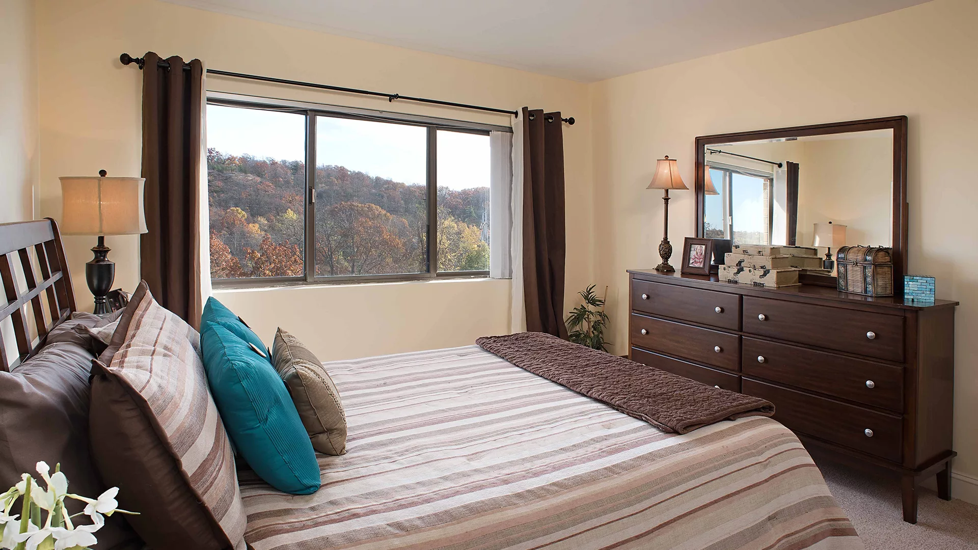 A cozy bedroom with a striped bedspread and a view of the outdoors.
