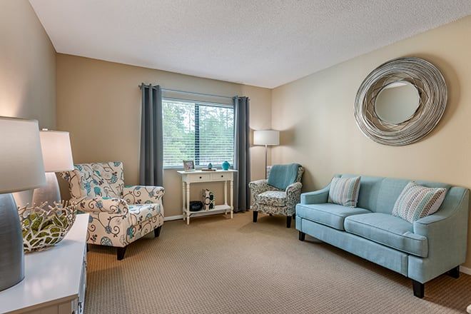 A cozy living room with a blue sofa, patterned armchair, and soft lighting.