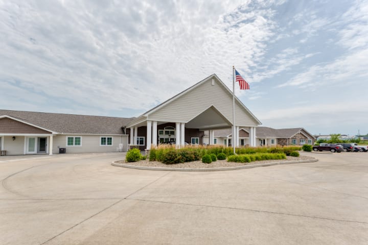 Front view of a building with a flag and parking area.