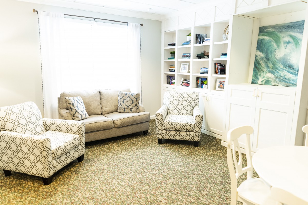 A cozy living room with a sofa, armchair, and built-in bookshelf under natural light.