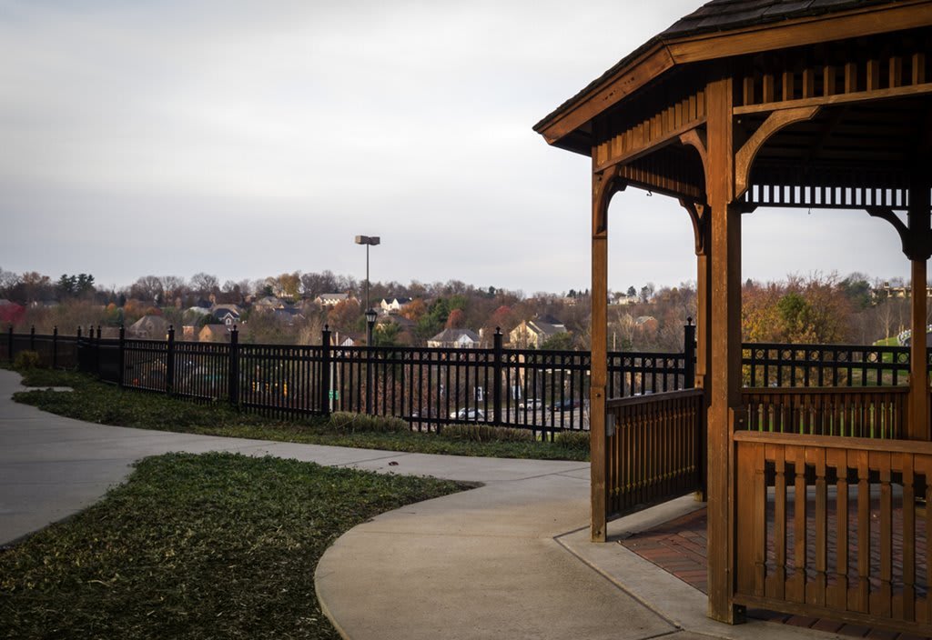 A wooden gazebo overlooking a town with a water tower in the distance under an overcast sky.
