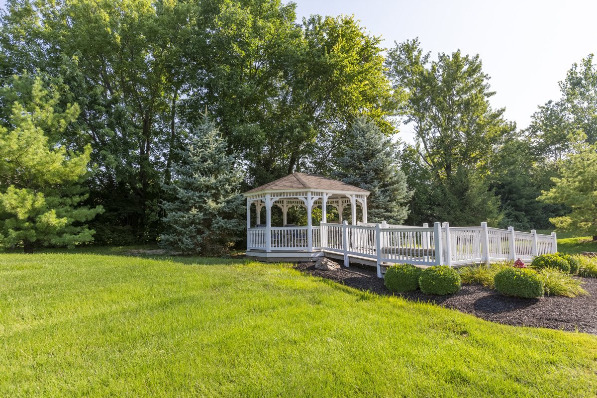 A quaint gazebo surrounded by lush greenery in a tranquil garden.