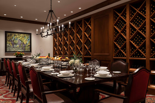 An elegant dining room featuring a beautifully set table and an impressive wine storage area.