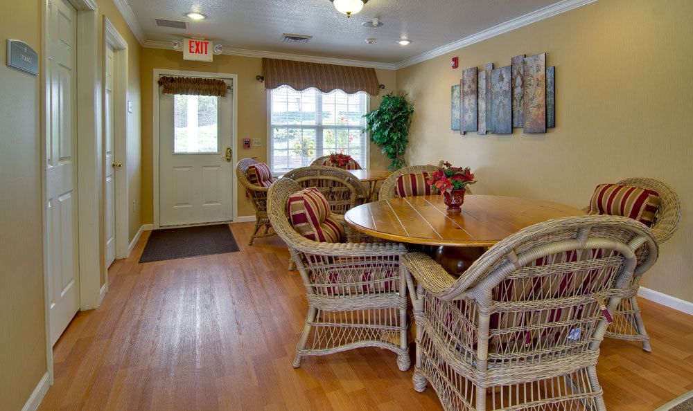 A cozy dining area featuring wicker chairs and a round wooden table, with warm lighting and decor.