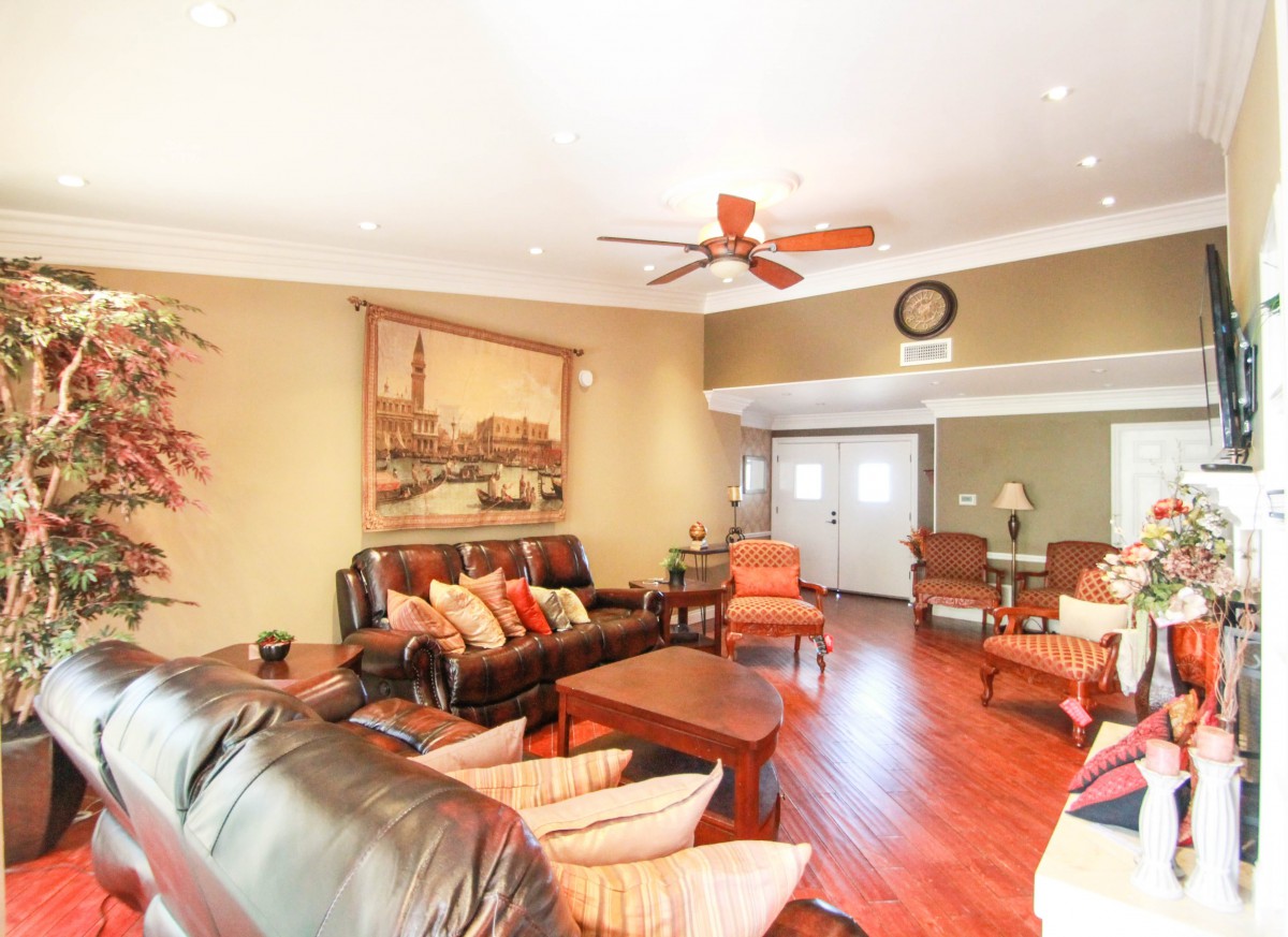 A cozy living room with comfortable seating, artwork on the wall, and a ceiling fan.