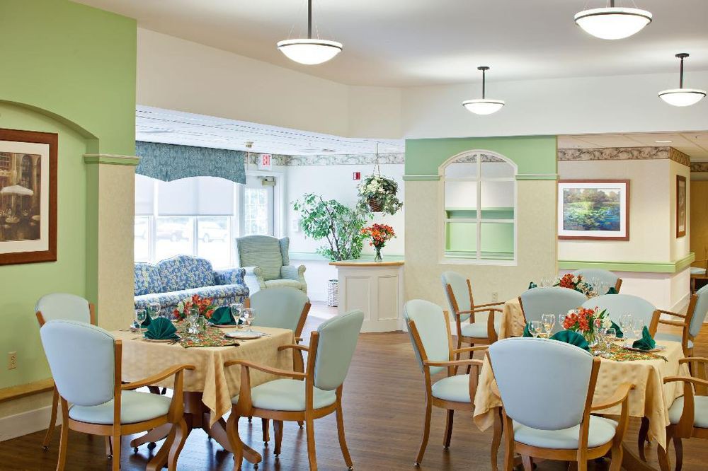A well-lit dining area with tables, chairs, and decorative elements including plants and flowers.