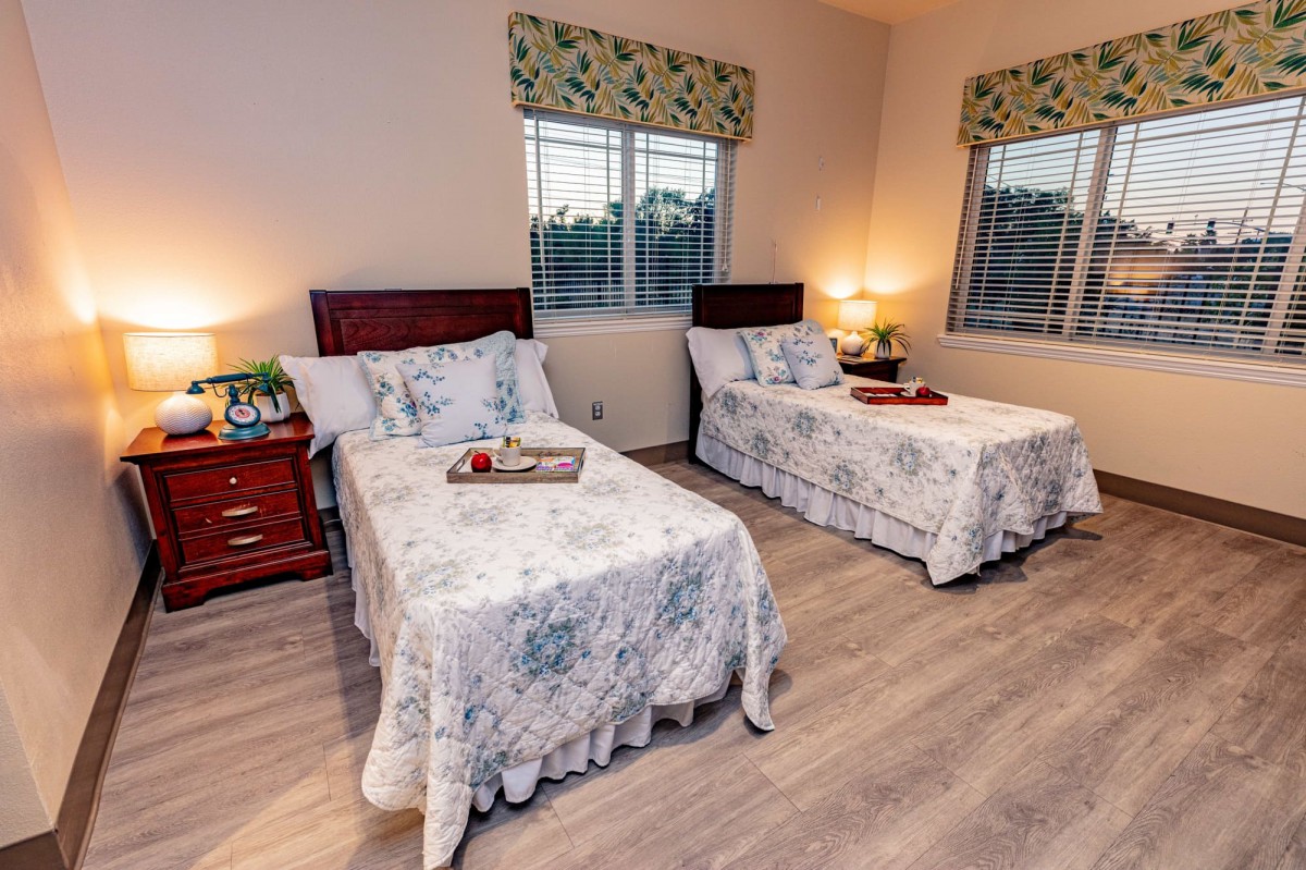 A cozy bedroom with twin beds, floral patterned bedding, and warm lighting.