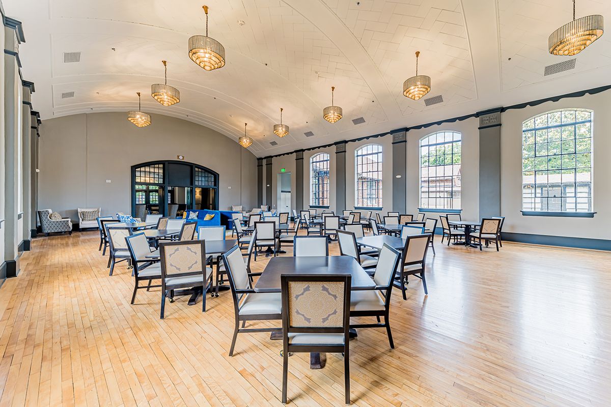Spacious dining area with tables and chairs, featuring large windows and elegant lighting.